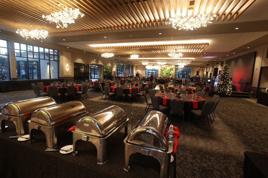 A banquet room set for a holiday dinner, with chafing dishes in the foreground and round tables beyond