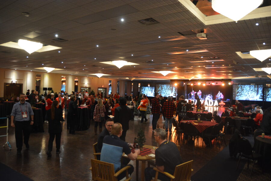 Guests at a Bingemans holiday party, with a live band on stage and tables set with plaid linens